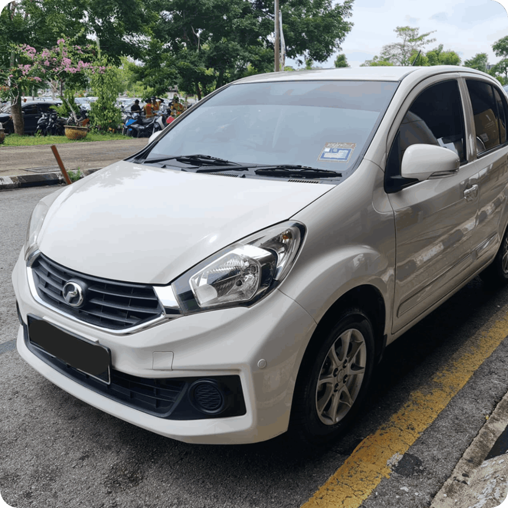 White compact rental car parked in an outdoor lot with tinted windows and alloy wheels.