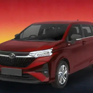 Red Perodua MPV against a warm evening skyline background.