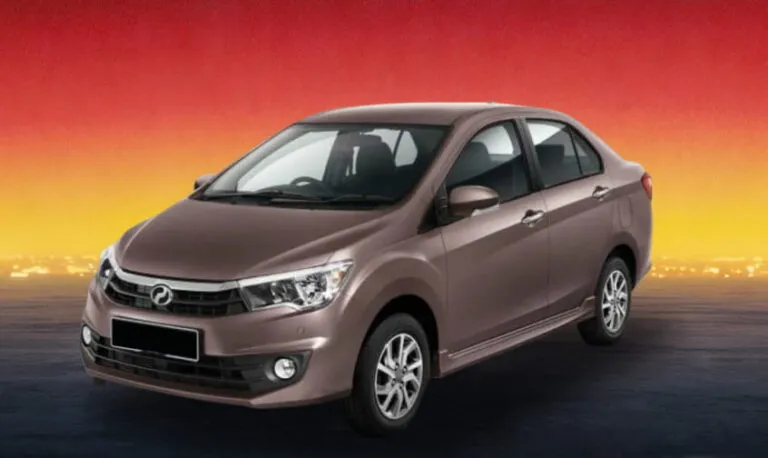 Brown compact sedan car on a dark road at sunset with red and yellow sky.