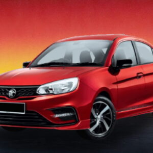 Red compact sedan car on a dimly lit road with a warm evening glow.
