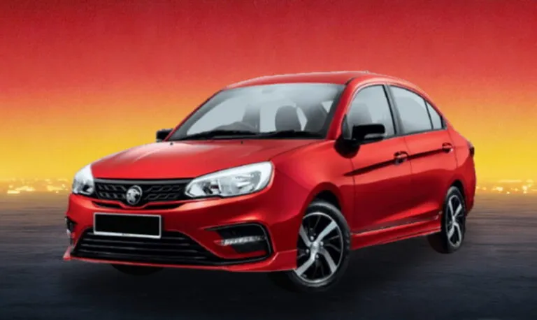 Red compact sedan car on a dimly lit road with a warm evening glow.