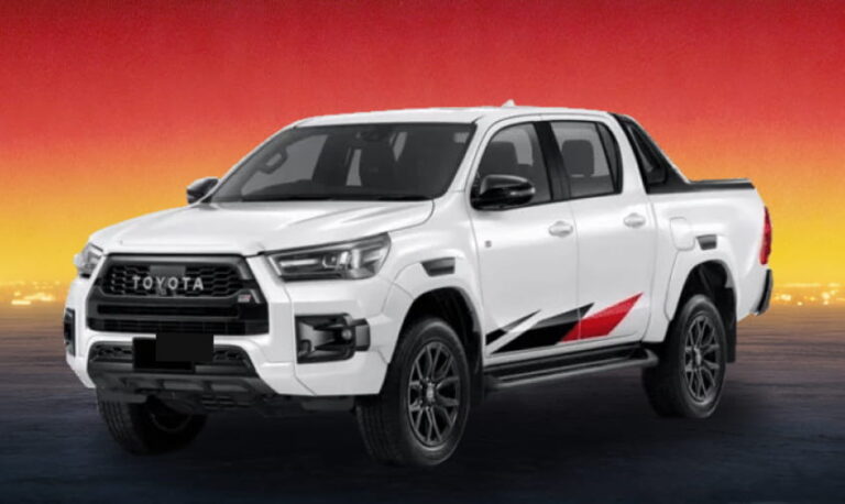 White Toyota Hilux pickup against a sunset background.