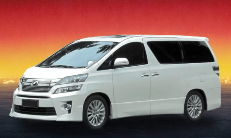 White Toyota MPV against a vibrant red and amber twilight backdrop.