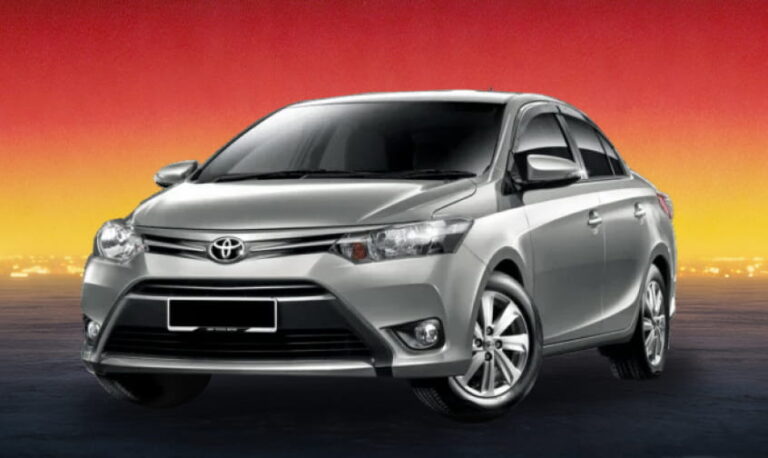 Silver Toyota sedan against a red and yellow sunset background.